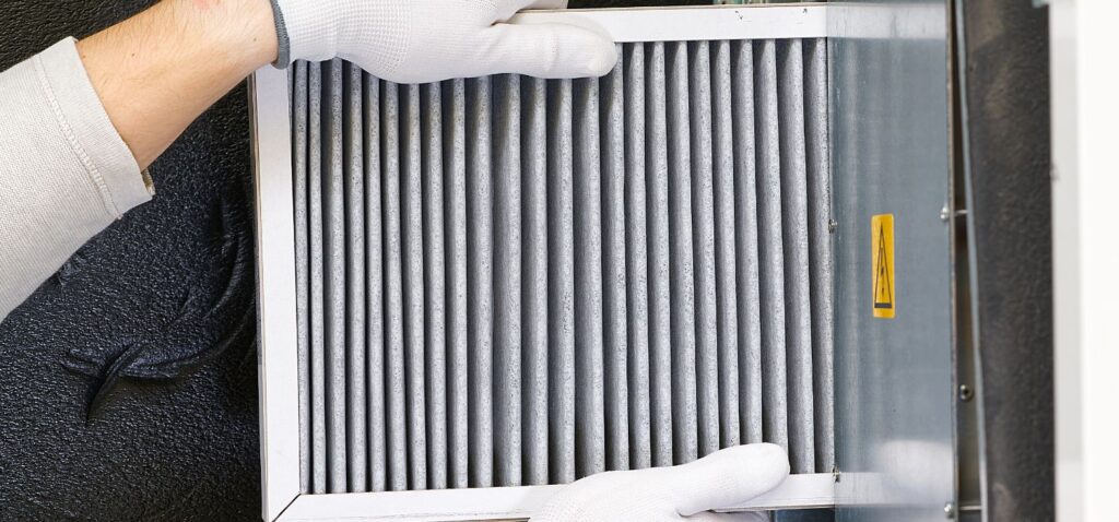 A technician installs a clean furnace air filter during an annual heating tune-up to improve airflow, efficiency, and indoor air quality.