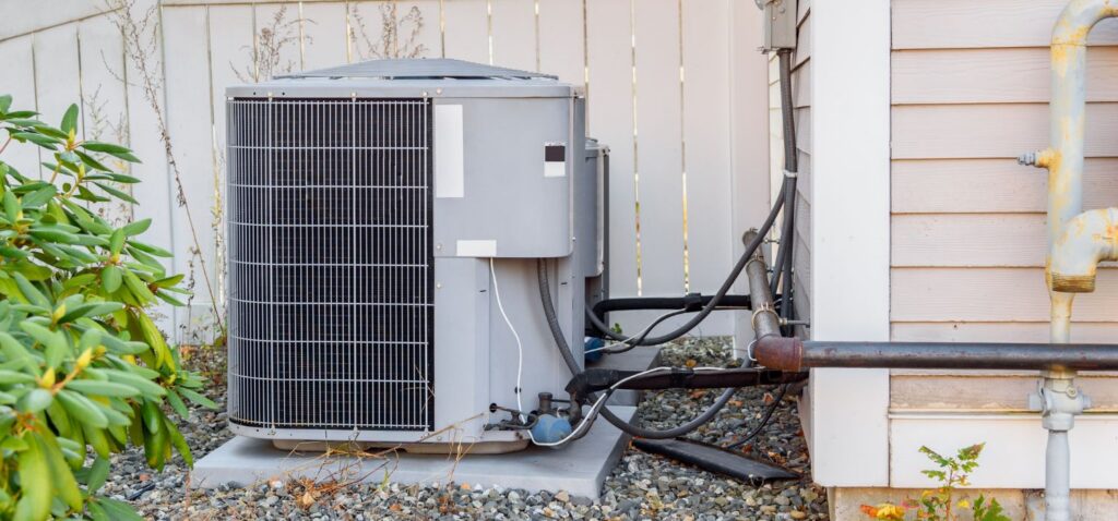 Outdoor energy-efficient HVAC condenser unit installed beside a home in a residential yard.